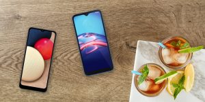 Samsung Galaxy A02 and moto e (2020) on a tabletop with some summer drinks in the lower right