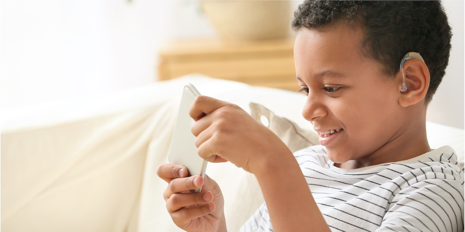 Android accessibility suite banner image: boy with a hearing aid using a mobile phone