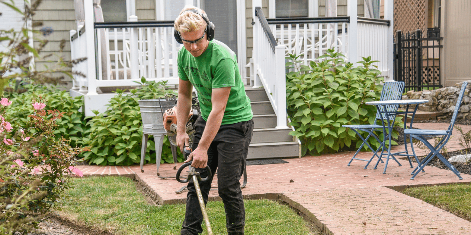 A young person offers help around the house, trimming the grass in a front yard.