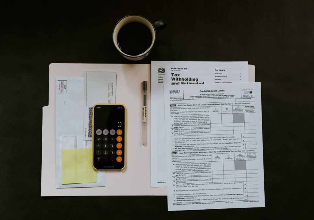 A desk with a phone, tax forms and a coffee on it.