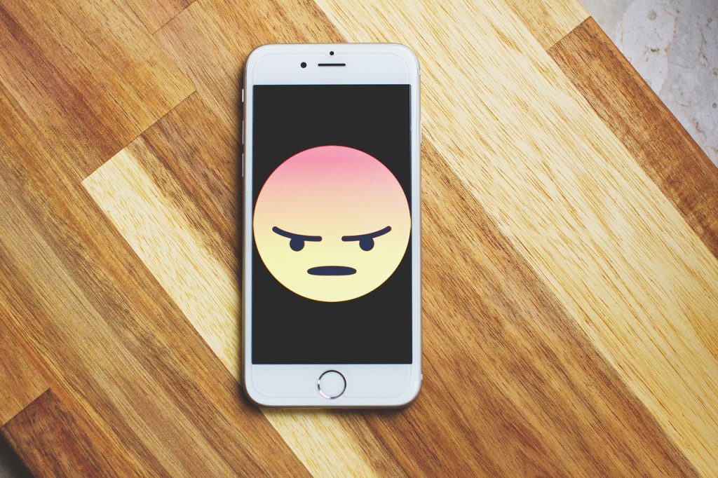 An iPhone with an angry emoji face taking up the majority of the screen.